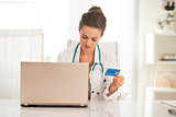 Medical doctor woman with credit card using laptop