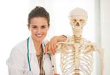 Portrait of smiling medical doctor woman near human skeleton ana