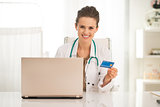 Medical doctor woman with credit card and laptop