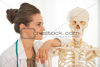 Portrait of medical doctor woman looking on human skeleton anato