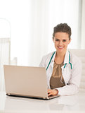 Portrait of happy medical doctor woman using laptop