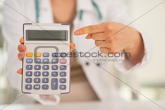 Closeup on medical doctor woman pointing on calculator