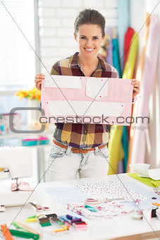 Happy seamstress showing pattern in studio