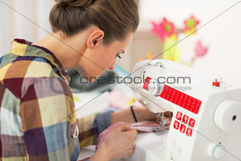 Seamstress working with sewing machine. rear view