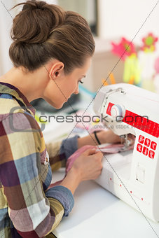 Seamstress working with sewing machine. rear view