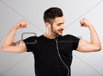 Man listen  music and looking his muscles