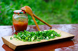 Chopped green onions on a cutting Board, on the background of tw