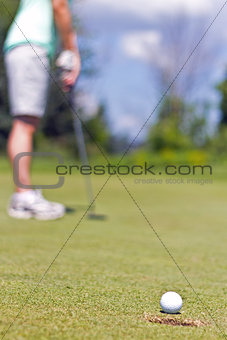 Woman sinking a putt on a golf green - selective focus