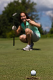 Woman putting the golf ball into the cup - selective focus