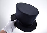 Male hand holding classic top hat 