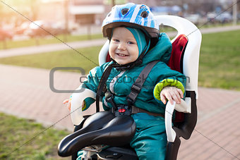 Cheerful little boy in a bike seat