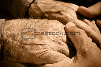 young man holding the hands of an old man