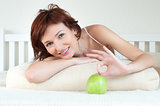 attractive young woman with an green apple at bed
