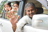 Indian family waving hands in car