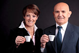 an elderly couple holding up two cups of espreso coffee