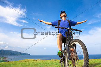 young man sitting on a  mountain bike and open arms to relaxing