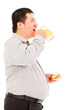 fat business man drinking beer mug and eating hamburger
