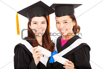 two smiling young graduate students holding a diploma
