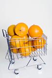 A shopping cart full of fresh whole oranges against a white background.