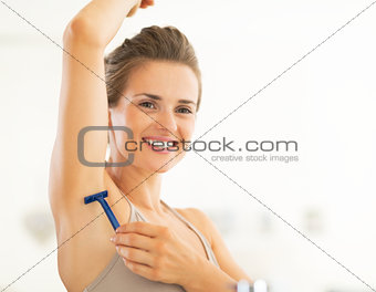 Portrait of happy young woman shaving armpit