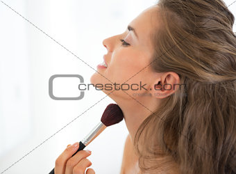 Portrait of young woman applying makeup