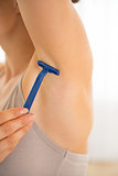 Closeup on young woman shaving armpit