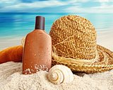 Straw hat with towel and lotion on the beach