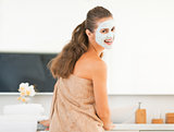 Smiling young woman wearing facial cosmetic mask