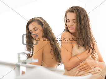 Relaxed young woman with long wet hair sitting in bathroom