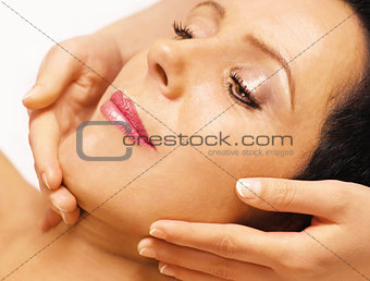  Woman lying, gets massage, reiki,  on her face 