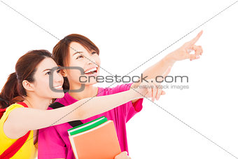 happy student girls holding books and pointing somewhere