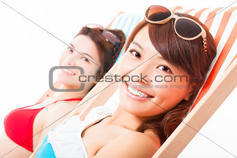 two young girl sunbathing and lying on a beach chair