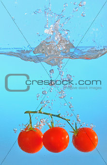 red tomatoes thrown into clear water