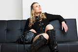 woman wearing black clothes with a handbag sitting on sofa