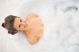 Happy young woman laying in bathtub
