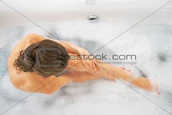 Happy young woman washing in bathtub