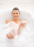Happy young woman playing with foam in bathtub
