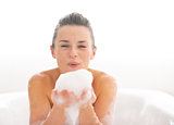Portrait of happy young woman playing with foam in bathtub