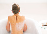 Young woman in bathtub. rear view