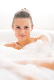 Portrait of happy young woman laying in bathtub