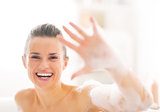 Portrait of happy young woman in bathtub showing foam