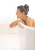 Young woman in bathtub looking on copy space