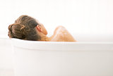 Young woman relaxing in bathtub. rear view