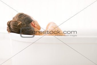 Young woman relaxing in bathtub. rear view