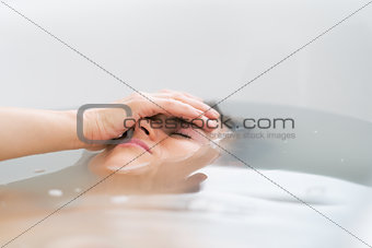 Frustrated young woman laying in bathtub