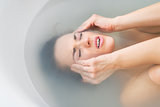 Stressed young woman laying in bathtub