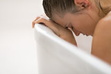 Stressed young woman sitting in bathtub