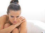Frustrated young woman sitting in bathtub