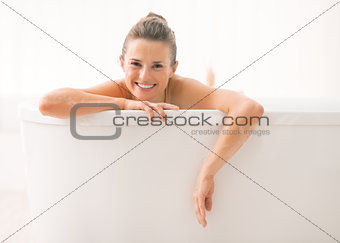 Young woman looking out from bathtub