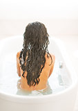 Young woman sitting in bathtub. rear view